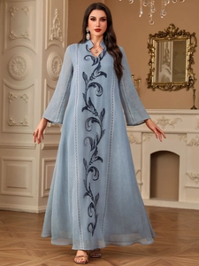 Detail of elegant light blue embroidery maxi dress featuring intricate vine patterns on the front