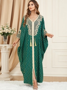 Dark green kaftan dress with golden embroidery and elegant tassels in a luxury ethnic style