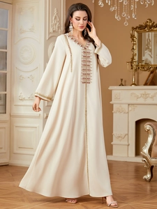 Close-up of beige kaftan with intricate gold embroidery and red beadwork detailing