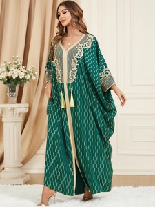 Detail of dark green kaftan dress with gold embroidery and decorative tassels