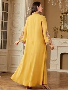 Detail of colorful embroidery on sleeve and neckline of yellow long sleeve kaftan dress