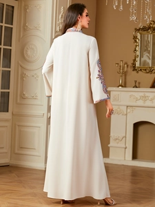 Detail der aufwendigen Blumenstickerei am Stehkragen einer eleganten weißen Abaya-Robe