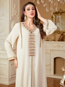 Detail of gold embroidery and red beads on an off-white kaftan dress neckline