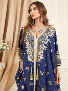 Détail de la broderie dorée sur caftan bleu foncé avec col en V et détails à gland