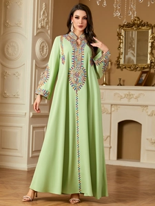 Close-up of ethnic embroidery on light green long-sleeved kaftan dress with v-neck detail