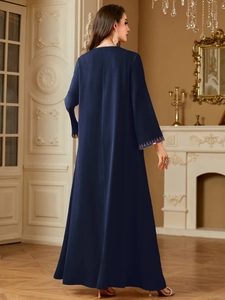 Detail view of ethnic floral embroidery on sleeves of a navy blue satin abaya dress