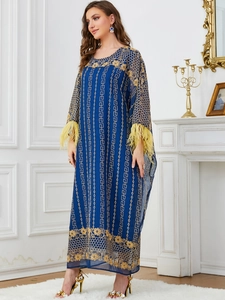 Vue détaillée du caftan bleu foncé avec broderie dorée et poignets en plumes jaunes
