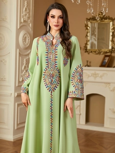 Detailed view of colorful heavy embroidery and sequins on a light green abaya dress