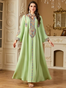 Detail showing intricate ethnic embroidery on the neckline and front of the green maxi dress