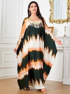 Kaftan maxi dress with green wave print and gold fringe neckline on a model in a room