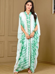 Close-up of white plus size kaftan featuring green leaf patterns and wide batwing sleeves