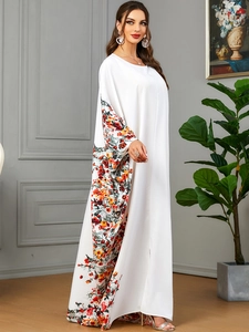 Détails de l'imprimé floral vibrant sur une robe longue blanche à manches chauve-souris