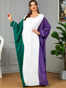 Detail view of contrast color splicing on a long loose kaftan dress with green and purple panels