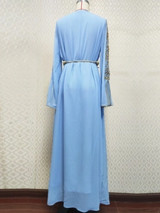 Détail de la robe brodée bleu clair avec motifs floraux dorés et ceinture à la taille
