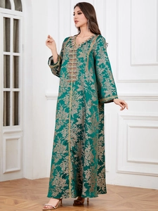 Close-up of golden floral embroidery and colorful beadwork on dark green kaftan dress