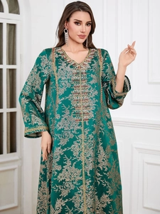 Close-up of emerald green kaftan dress with gold floral embroidery and beaded neckline