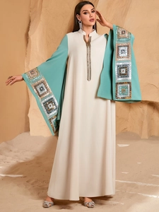 Elegant off-white and green kaftan with sequined sleeves in a desert landscape setting