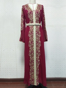 Détails de broderies florales dorées et de paillettes sur le col d'un caftan bordeaux