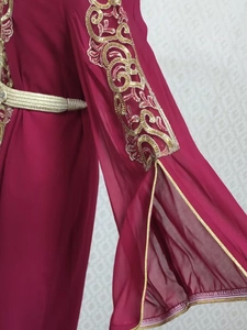 Détail des broderies dorées et de la ceinture tressée sur une robe caftan bordeaux