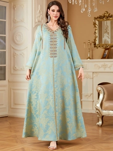 Detail showing jacquard floral pattern and intricate bead embroidery on a blue Kaftan gown