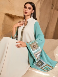 Elegant beige and lake blue kaftan dress with gold embroidery in a desert landscape