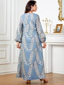 Détails d'une robe longue bleu clair avec broderie de feuilles dorées et manches lanternes