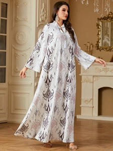 Détail du col en V avec cordons à glands sur une robe longue à imprimé paisley élégante