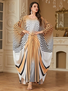 Close-up of elegant kaftan dress with orange and black geometric patterns and batwing sleeves