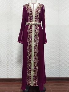 Détail de la broderie dorée complexe et ceinture sur une robe caftan bordeaux