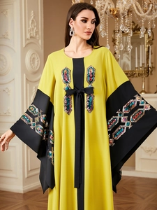 Close-up of ethnic sequin embroidery on sleeves of a yellow and black Kaftan dress