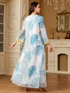 Elegant white maxi dress with blue tropical print and gold sequined cuffs on a model
