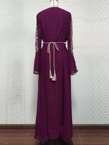 Détail de broderies dorées sur manches longues d'une robe longue violette à glands