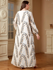Détail arrière d'une robe maxi blanche avec élégants motifs brodés noirs et dorés