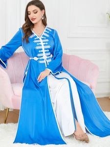 Detail of blue Kaftan featuring intricate white geometric embroidery and V-neck design