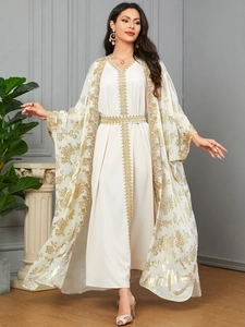 Detail of white kaftan dress with intricate gold floral embroidery and lace trim