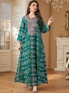 Détail de la broderie bohème et des motifs dorés sur la robe longue vert foncé