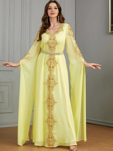 Detailansicht des hellgelben Kaftans mit goldener Spitzenstickerei und elegantem V-Ausschnitt