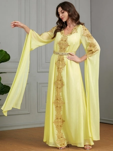 Detail eines gelben Kaftan-Kleides mit goldener Spitzenstickerei und weiten Schlitzärmeln