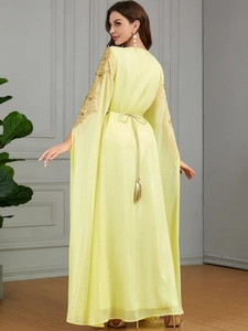 Detail eines gelben Kaftan-Kleids mit Goldstickerei am Ärmel und Quastengürtel