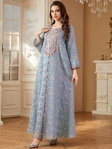 Détail de la broderie ethnique et des perles sur une robe caftan longue bleu clair