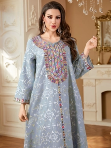 Détails de broderies denses et paillettes sur une robe ethnique bleu clair
