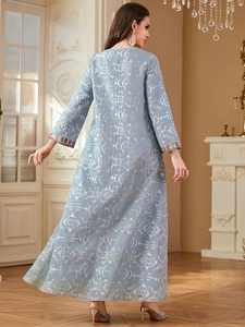 Détail de la broderie florale colorée sur la manche d'une robe bleue à motifs dorés