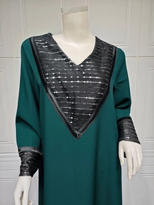 Close-up detail of silver sequin embroidery on the V-neck of a dark green dress