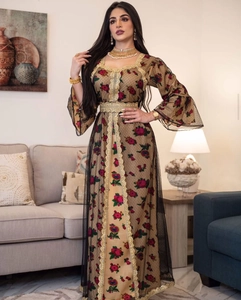 Detail of luxury ethnic maxi dress with floral print and gold embroidered lace edges