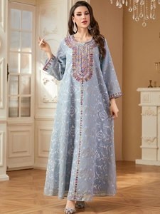 Détail de la broderie à paillettes sur l'encolure d'une robe kaftan bleu clair