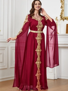 Detail von goldener Spitzenstickerei und rubinroten Juwelen auf dunkelrotem Kaftan-Kleid