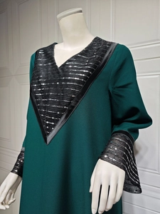 Detail of V-neckline with black sequins and flared sleeves on dark green ethnic dress