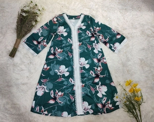 Détail de robe fleurie verte avec dentelle blanche délicate au col en V et aux poignets
