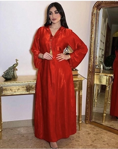 Detail of luxurious red satin kaftan featuring a hooded V-neckline and elegant bell sleeves
