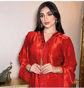 Detail of red hooded dress with pleated texture and elegant gold jewelry accessories